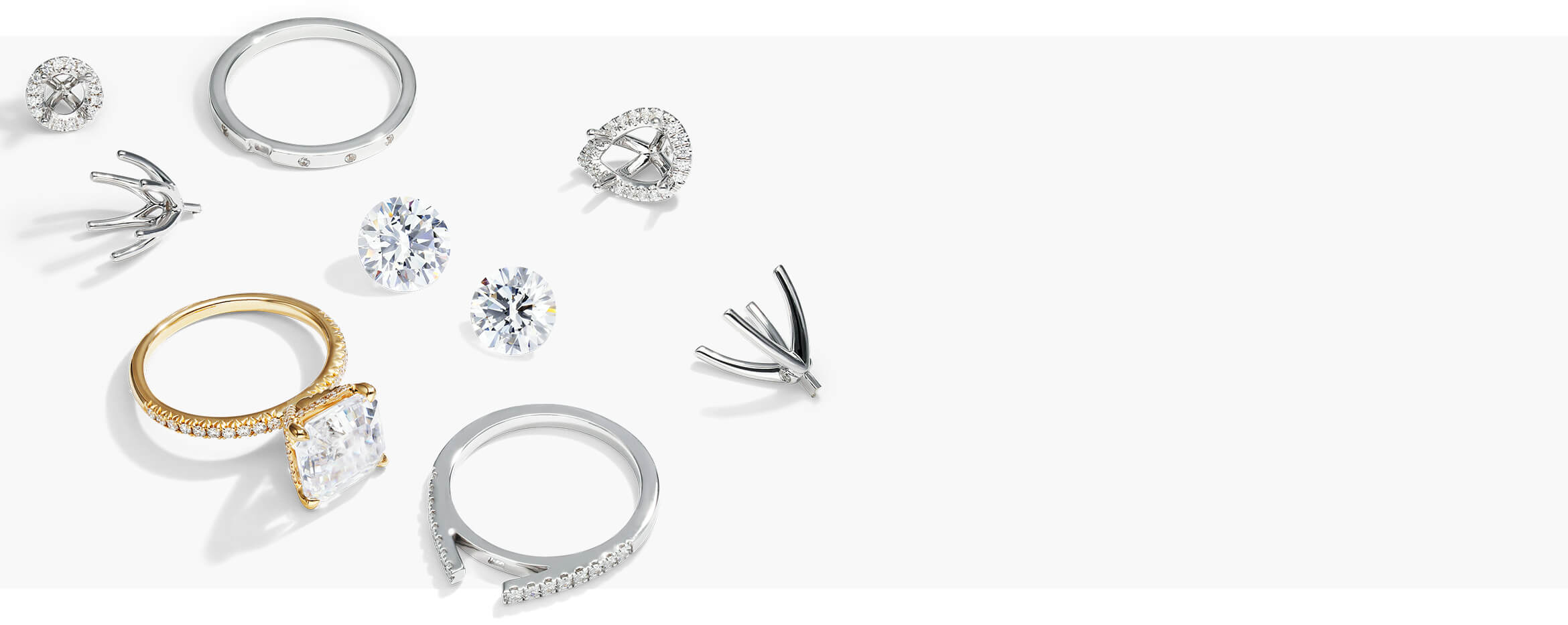 A display of loose diamonds, ring prongs and a yellow gold diamond engagement ring.