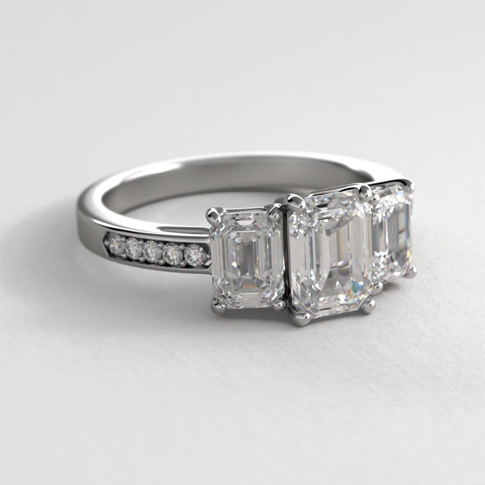 Emerald Cut Diamond Three Stone Engagement Ring With Pavé Set Diamonds In Platinum